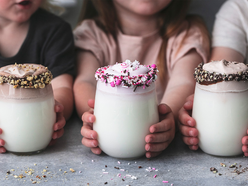Children holding three different flavors of whipped milk